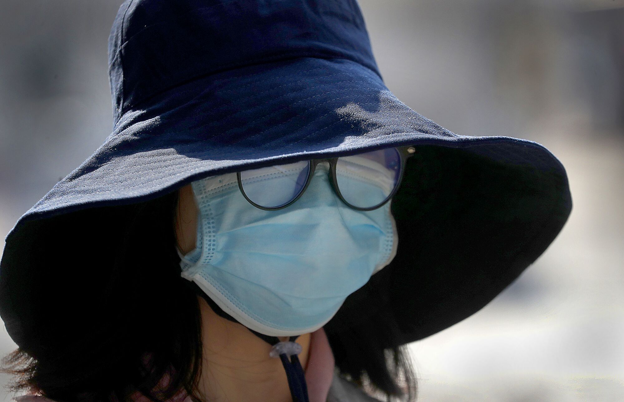 BRITAIN: A surgical mask nearly covers a woman's entire face as she seeks to protect herself from the coronavirus while taking a walk in London.
