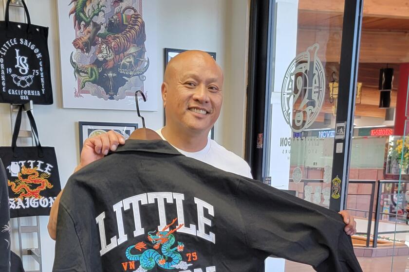 a man holds up a black sweatshirt with a drawing of a dragon holding oranges