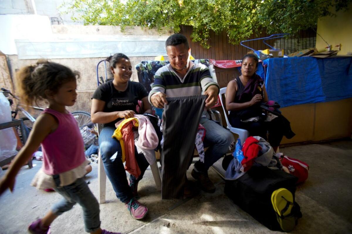 Gustavo Loza y su esposa, Leidy Rivas, llegaron a Tijuana después de viajar más de un mes desde El Salvador. Ambos revisan la ropa donada para reemplazar algunas de sus prendas (Nelvin C. Cepeda / San Diego Union-Tribune).