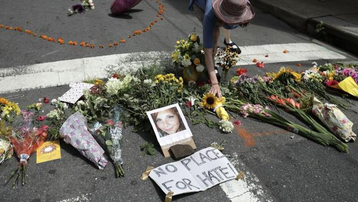A woman places flowers at an informal memorial to 32-year-old Heather Heyer, who was killed when a car plowed into a crowd of people protesting the white supremacist Unite the Right rally