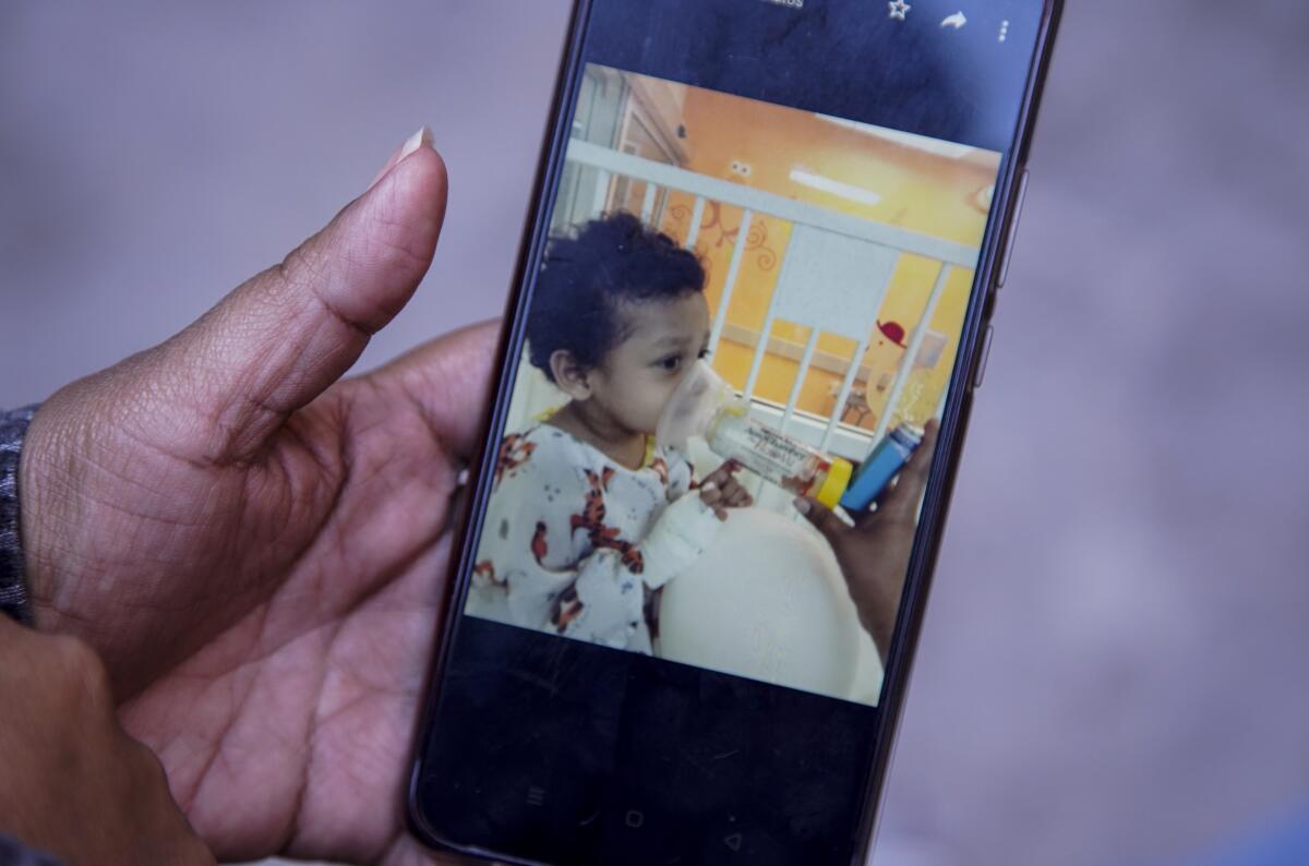 Ana sostiene el celular con las fotos de su hijo Carlitos en la oficina de Al Otro Lado