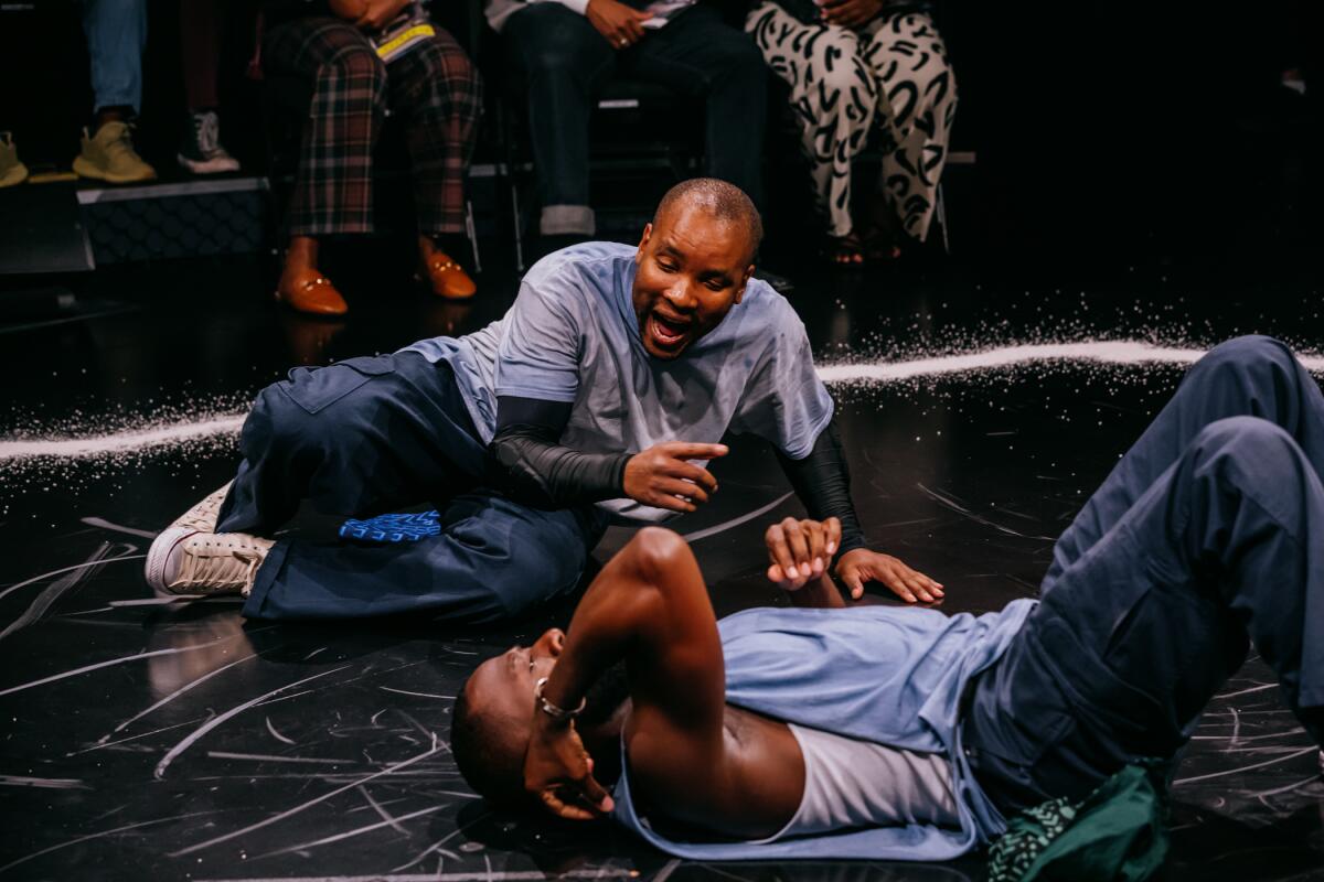 Two men lie on a stage in different positions near each other in 'The Brothers Size' at the Geffen Playhouse.