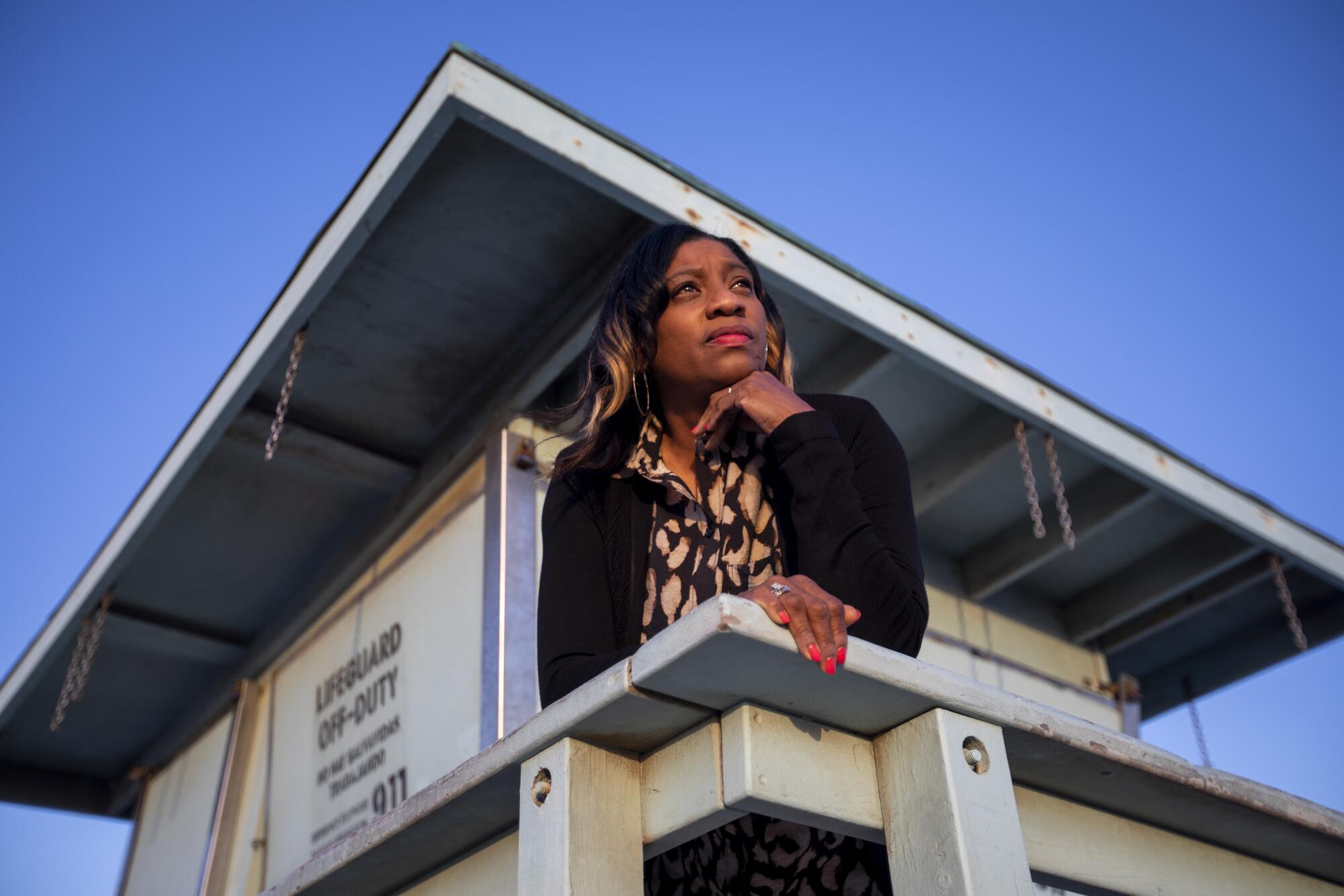 A woman looks out from a lifeguard tower