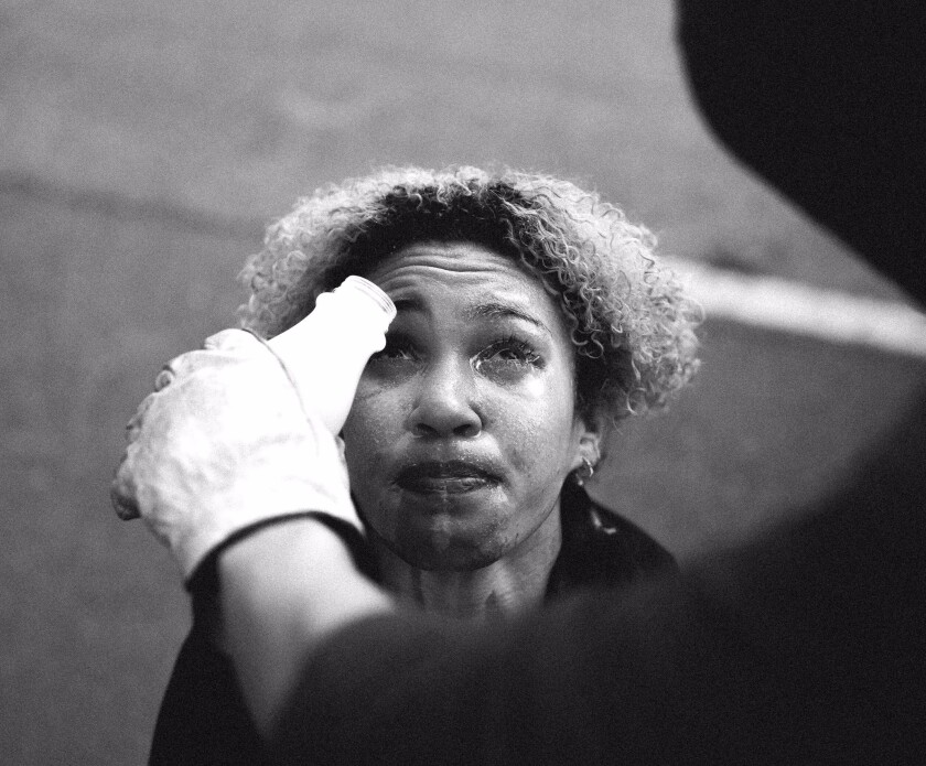 A protester helps wash Williams eyes out after she was pepper sprayed and shot with rubber bullets while protesting.