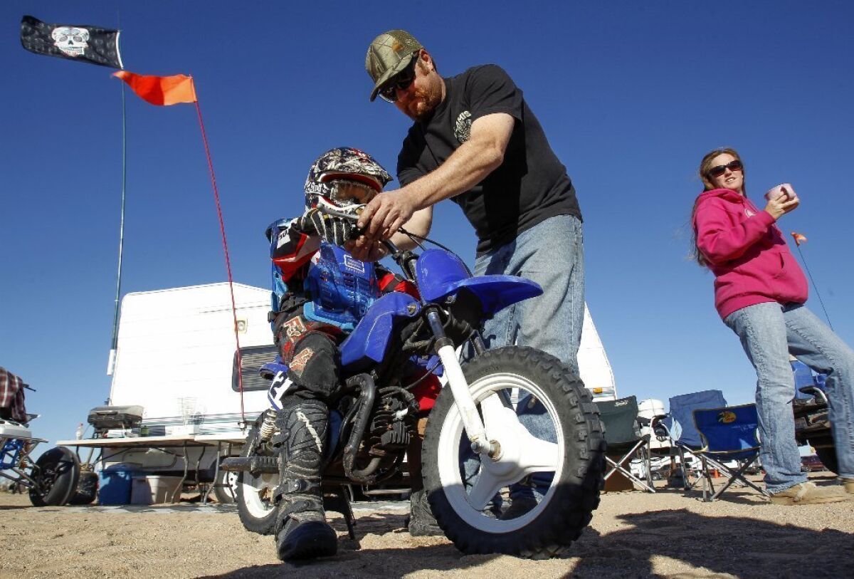 Lake Elsinore resident Les McDonlad gets his son Dane McDonlad, 7, ready to ride as the boy's mother, Melanie McDonald, looks on at the Imperial Sand Dunes on New Year's Day. / photo by Hayne Palmour IV * U-T