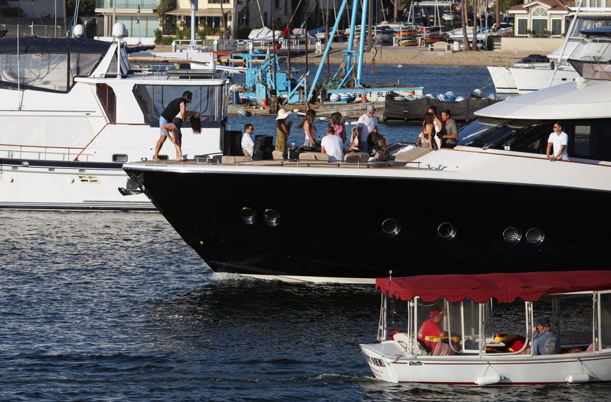 A couple dances on the tip of their boat during the 2021 War Heroes on Water Boat Parade.