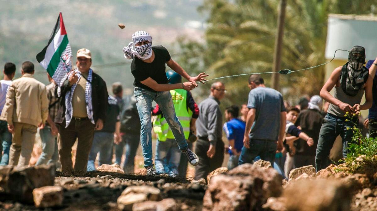 A Palestinian protester uses a slingshot to hurl stones toward Israeli security forces near Nablus, in the occupied West Bank.