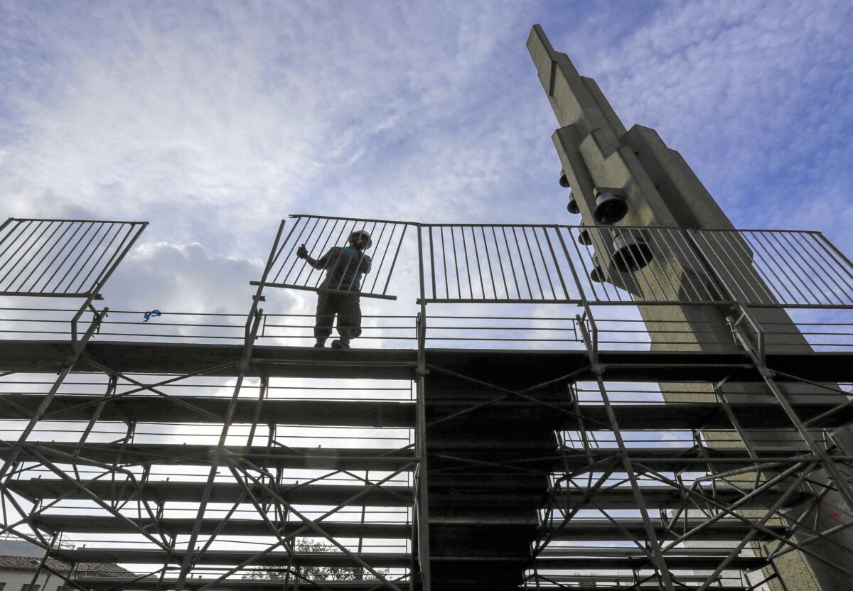 Jesus Esquivel installs a fence on bleachers in front of Gospel Siloam Church on Colorado Avenue in preparations for the Rose Parade in Pasadena.