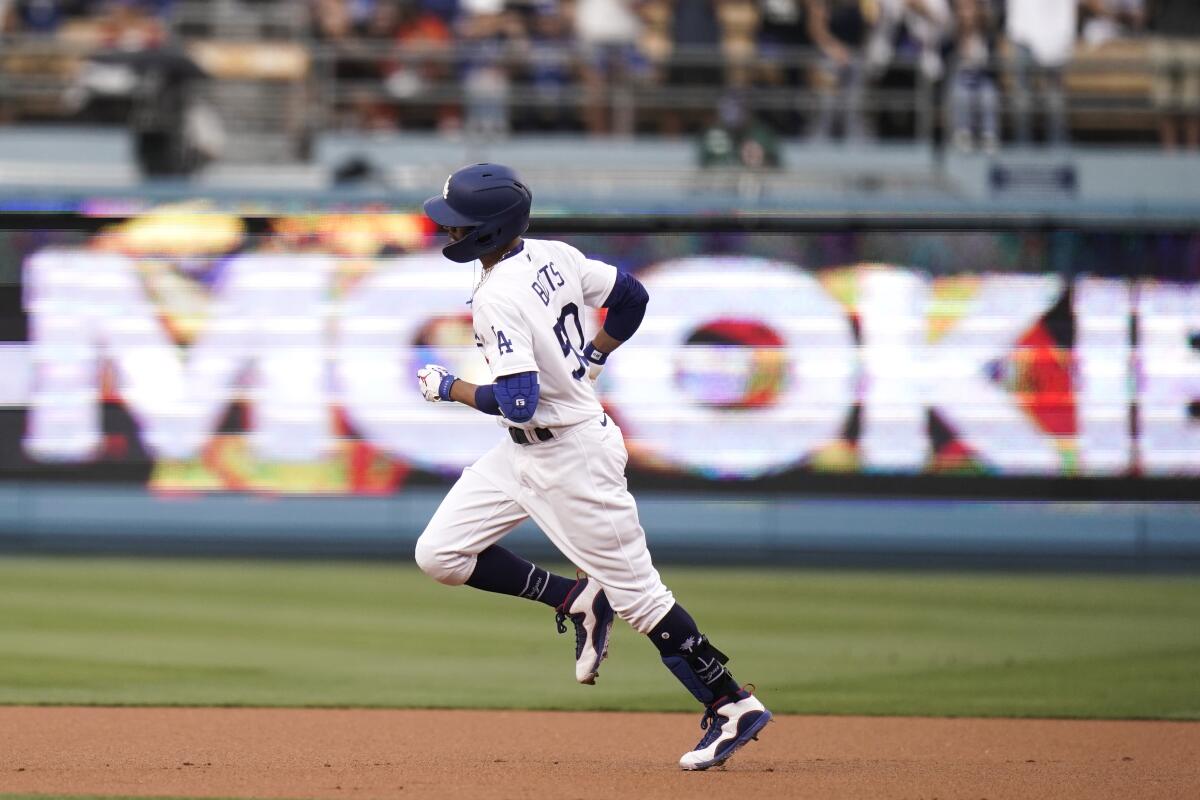 Dodgers' Mookie Betts rounds the bases in front of an electronic sign showing his name after hitting a home run