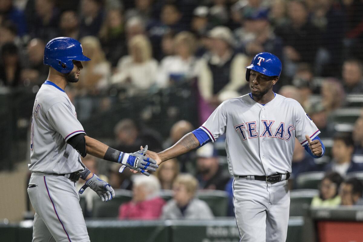 Rangers infielder Jurickson Profar, right, is congratulated by Nomar Mazara after scoring on a double by Ian Desmond,in a game against the Mariners.