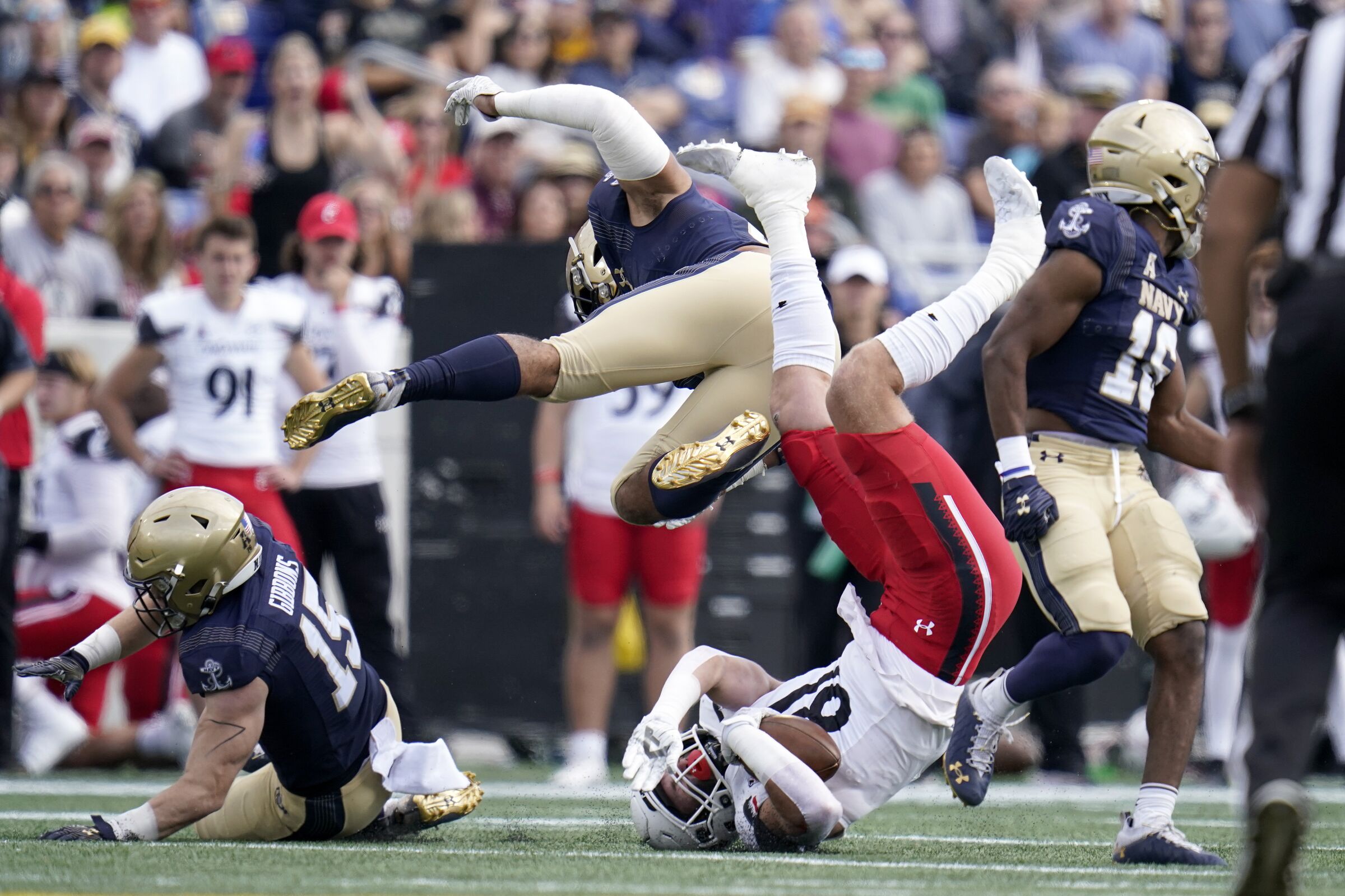 Navy linebacker Nicholas Straw, top, upends Cincinnati tight end Josh Whyle while making a tackle.