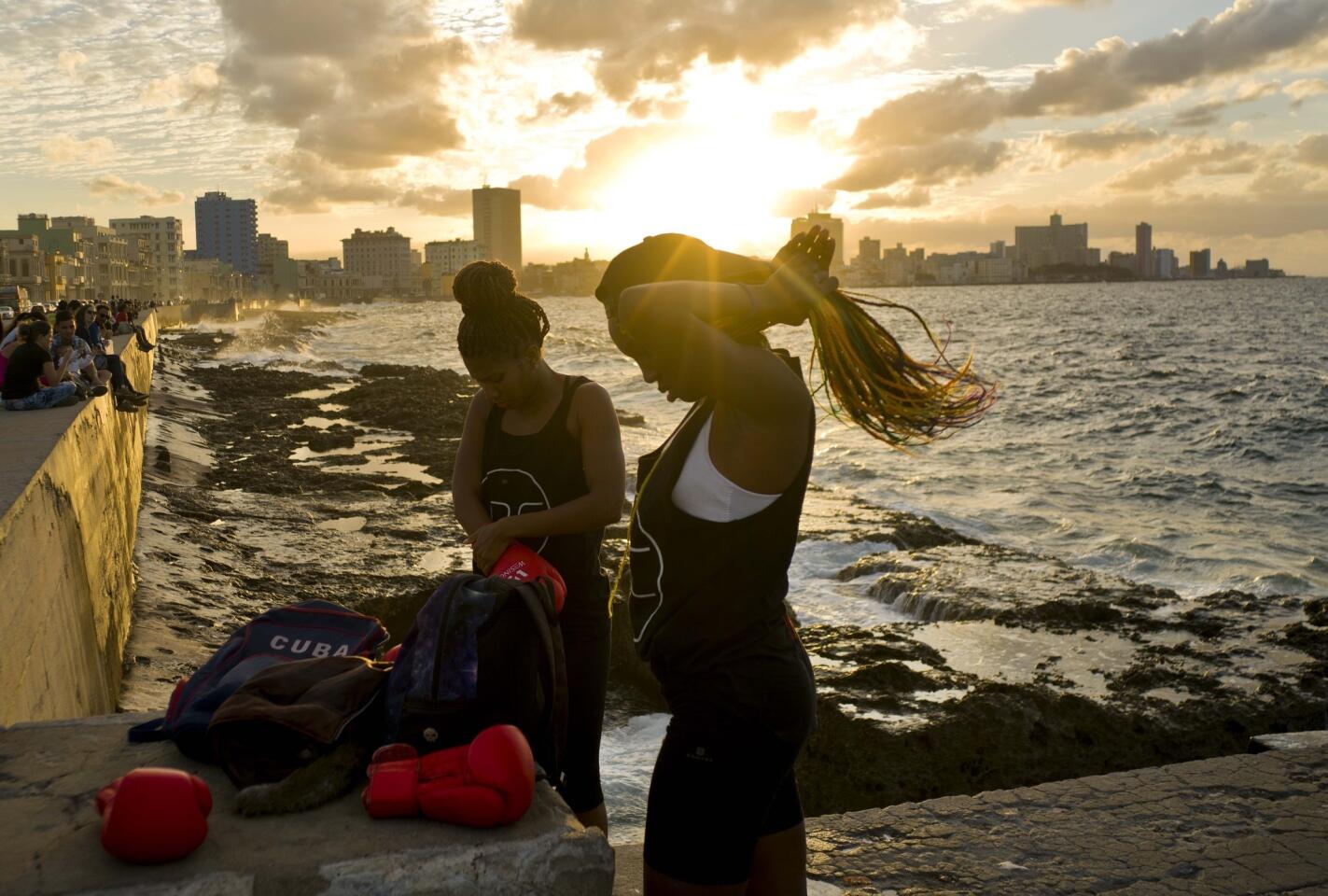 Las boxeadoras Idamerys Moreno (i) y Legnis Cala se preparan para una sesión de fotos en el Malecón de La Habana, en Cuba. Moreno entrena al menos dos horas al día después de salir de su trabajo; pelea tanto con hombres como con mujeres.