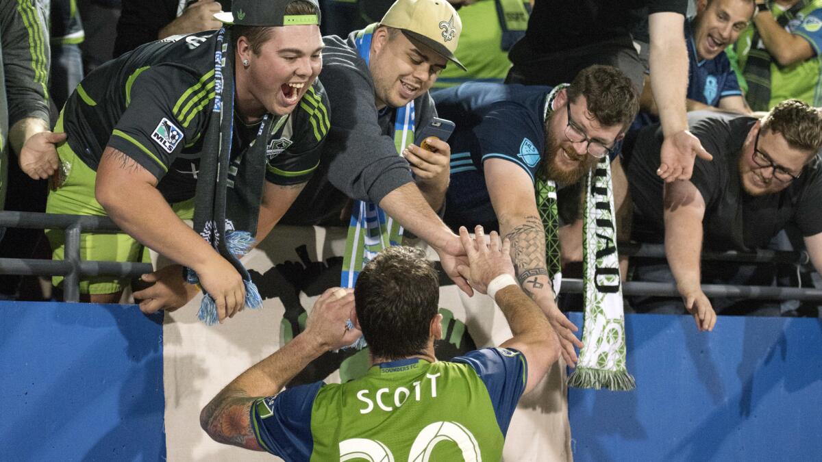 Sounders defender Zach Scott celebrates with fans after the club advanced to the Western Conference finals on Sunday.