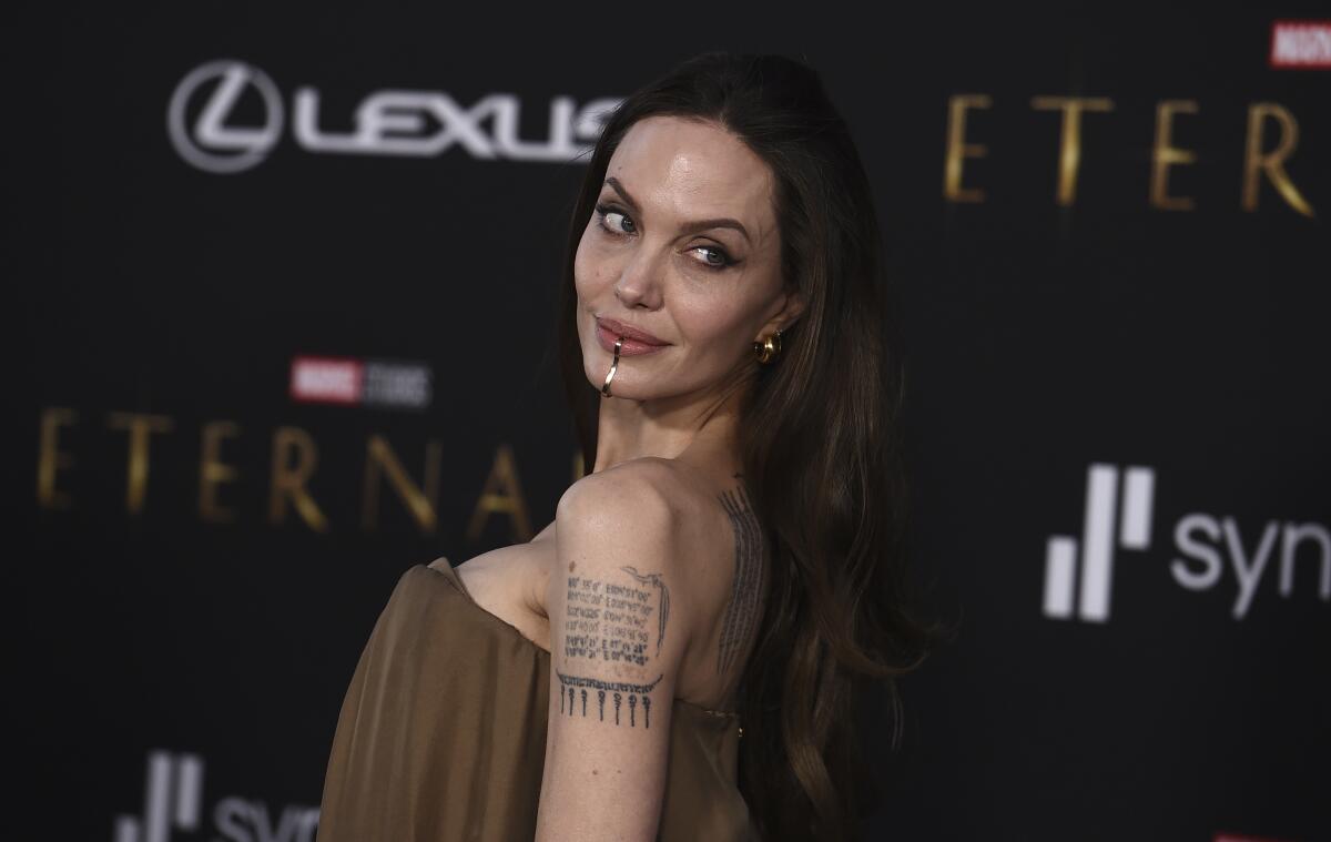 Angelina Jolie in an off-the-shoulder dress posing for pictures at a red carpet premiere