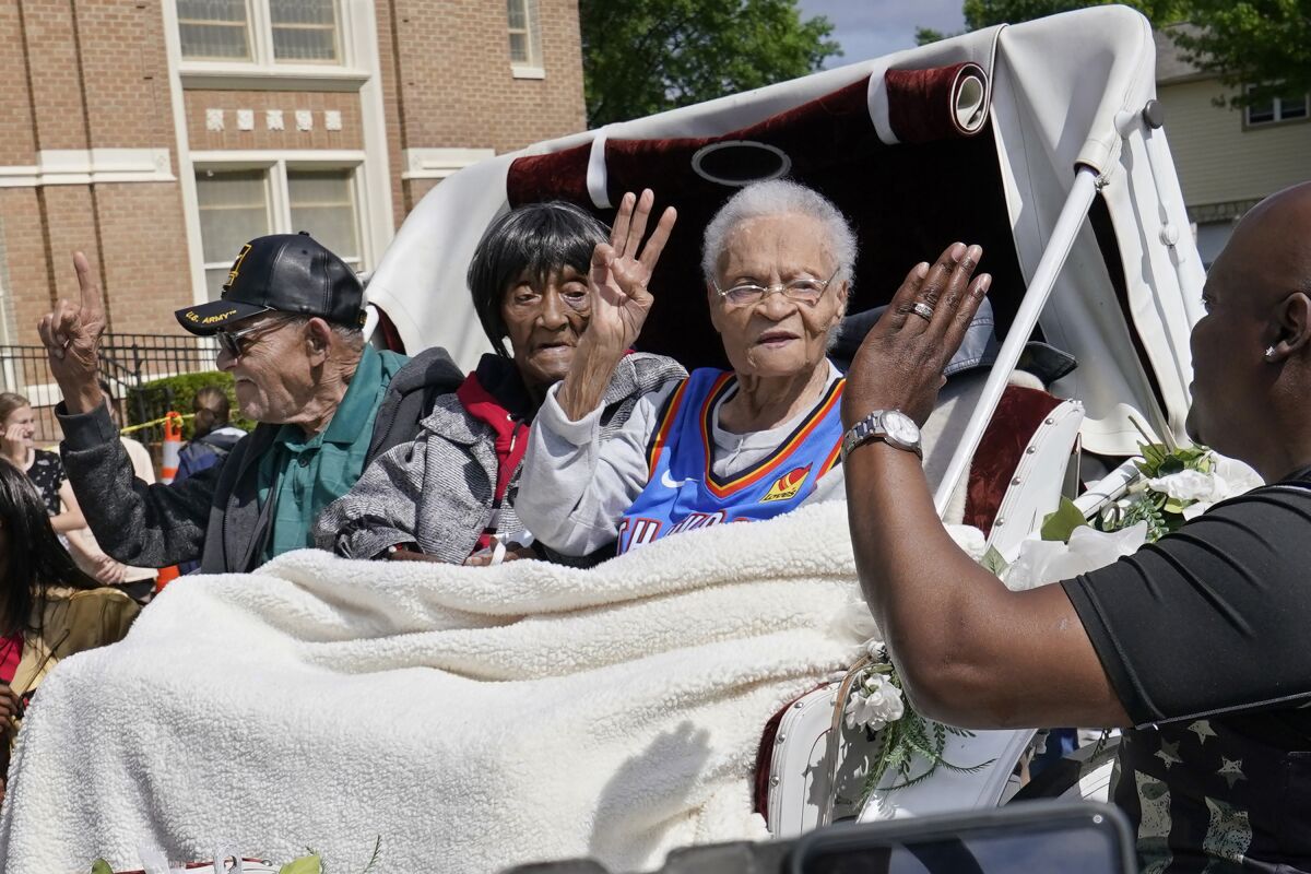 FILE - Tulsa Race Massacre survivors, from left, Hughes Van Ellis Sr., Lessie Benningfield Randle, and Viola Fletcher, wave and high-five supporters from a horse-drawn carriage before a march in Tulsa, Okla., on May 28, 2021. The three known living survivors of the 1921 Tulsa Race Massacre are receiving a $1 million donation from a New York philanthropic organization. They will share the donation. (AP Photo/Sue Ogrocki File)