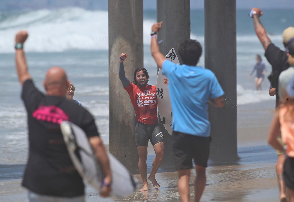 Ian Gouveia is all smiles as his support crew rushes to congratulate him at the U.S. Open of Surfing on Friday.