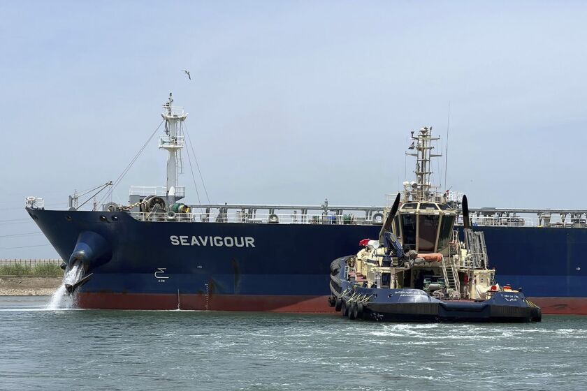 In this photo provided by Egypt's Suez Canal Authority, a tugboat pushes the Seavigour after it suffered a mechanical malfunction at the 12 kilometers (7.5 miles) mark of the canal, Egypt, Sunday, June 4, 2023. Seavigour, which transporting crude oil, broke down in a single-lane part of Egypt's Suez Canal, briefly disrupting traffic in the global waterway, Egyptian authorities said. (Suez Canal Authority via AP)