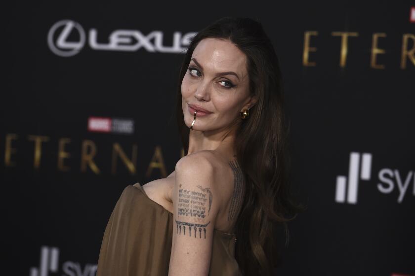 Angelina Jolie in an off-the-shoulder dress posing for pictures at a red carpet premiere