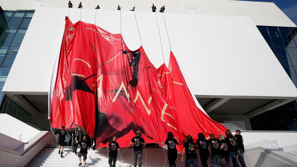 Workers set up the official poster of the 70th annual Cannes Film Festival on the Palais des Festivals facade, in Cannes, France. The poster displays a photogram of Italian actress Claudia Cardinale.