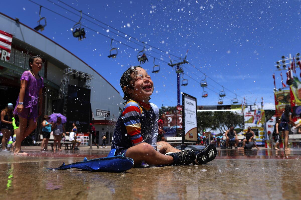 Mason Rose, 2, tries to beat the heat at the Orange County Fair in Costa Mesa, which runs through Aug. 11. Temperatures are expected to dip slightly into the weekend but will remain higher than average.