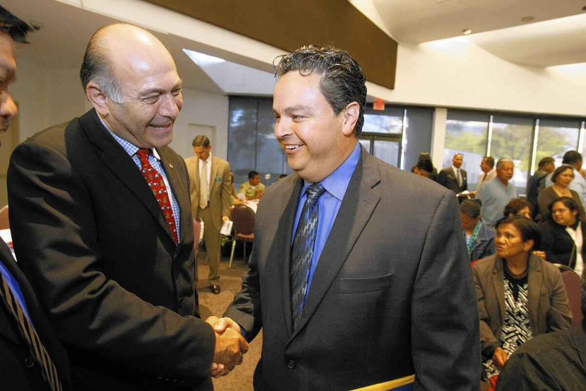 Albert Robles said he has no plan to drop either of his elected positions. Above, Kourosh Hangafarin, left, greets Robles before he is sworn in last year as a Carson City Councilman.