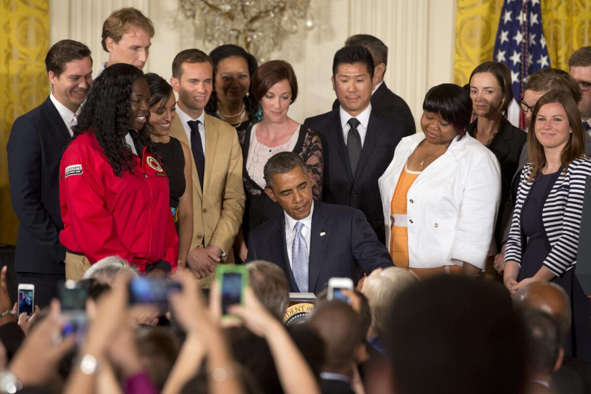 Surrounded by college students in the East Room of the White House, President Obama signs an executive order that could let millions of student loan borrowers reduce their monthly debt payments.