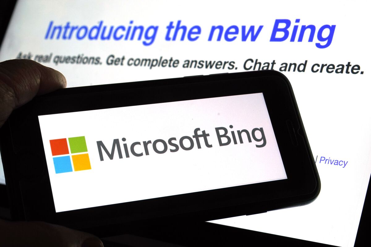 The Microsoft Bing logo displayed on a phone, and a computer screen in the background