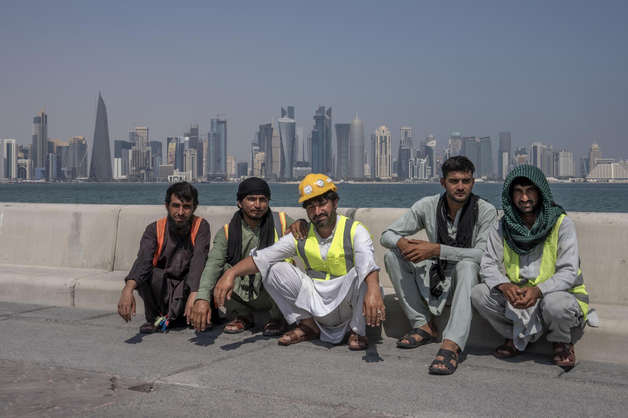 Pakistani migrant laborers pose in front of the skyline of Doha.