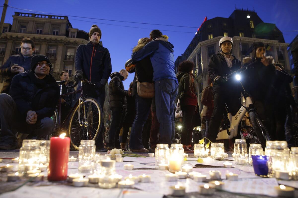 People hold each other at a makeshift memorial in front of the stock exchange at the Place de la Bourse.