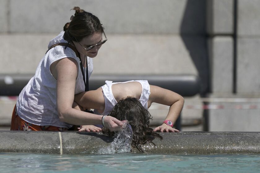 A person wets their hair in a fountain at Trafalgar Square in central London, Tuesday July 19, 2022. Millions of people in Britain woke from the country’s warmest-ever night on Tuesday and braced for a day when temperatures could break records, as a heat wave scorching Europe walloped a country not built for such extremes (Aaron Chown/PA via AP)