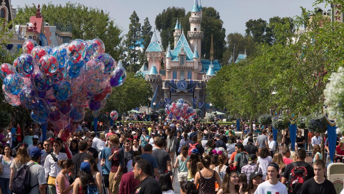 A large crowd strolls down Main Street, U.S.A., in 2015 during Disneyland's 60th anniversary celebration. Theme park ticket prices have increased faster than other entertainment costs since 2007.