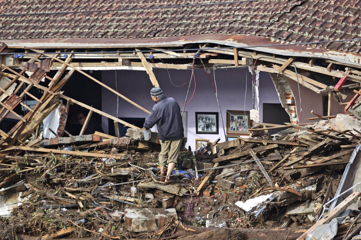 A man inspects the damage to a house following a flash flood in Bulukerto village, Batu, East Java, Indonesia, Friday, Nov. 5, 2021. Rivers on the slopes of Mount Arjuno overflowed their banks on Thursday and their muddy waters inundated five hamlets in East Java province, leaving a number of people killed or missing. (AP Photo/Trisnadi)