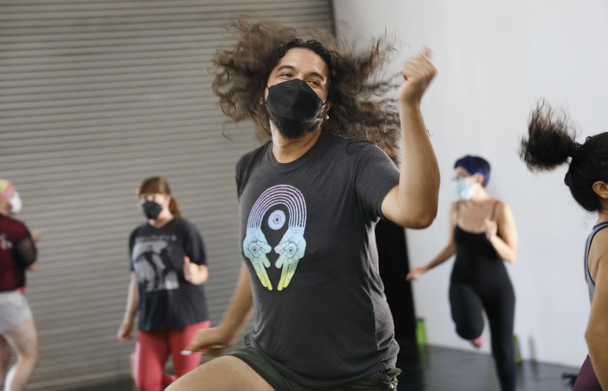A person with long hair flying does aerobic dance moves.