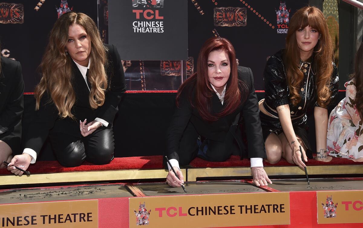 Lisa Marie Presley, left, Priscilla Presley and Riley Keough write their names in cement at TCL Chinese Theatre