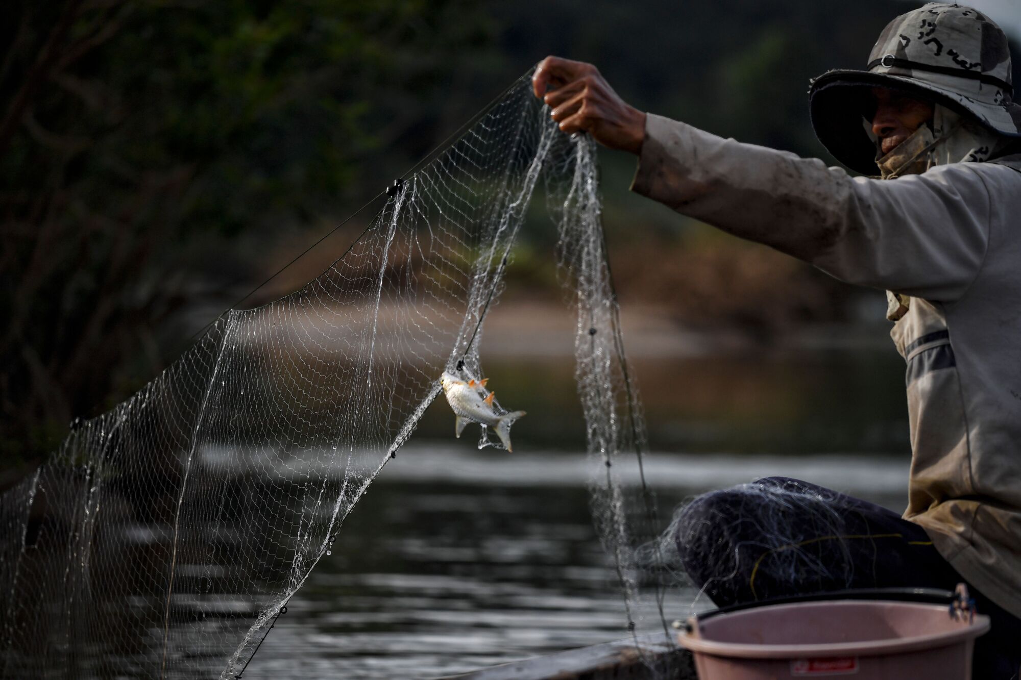 A fisherman checks his net along the Mekong River