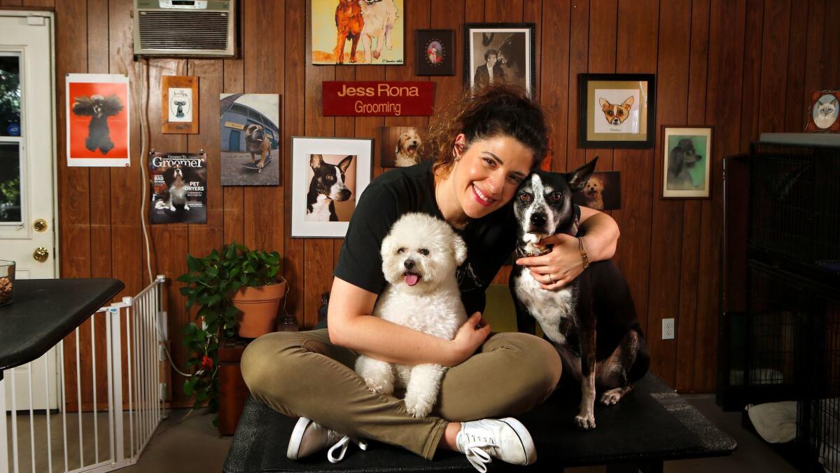 Dog grooming artist Jess Rona with her two dogs, Meemu, left, a poodle mix, and Chupie, a sato, at her grooming studio in Los Angeles.