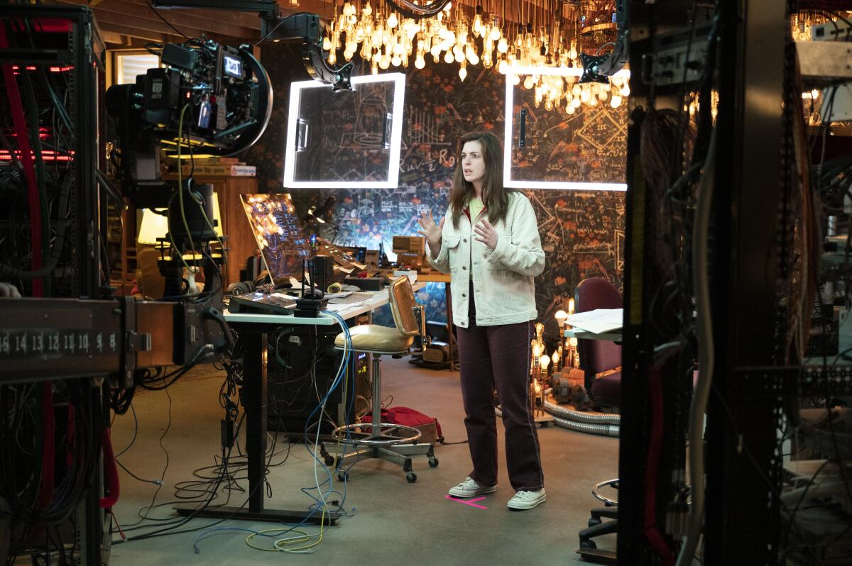 The actor Anne Hathaway on a cluttered set, flanked by two rectangular fluorescent panels
