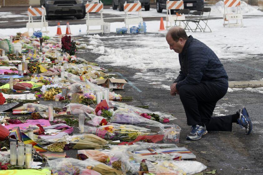 Colorado Gov. Jared Polis kneels in front of a memorial set up outside Club Q in Colorado Springs, Colo., Tuesday, Nov. 29, 2022. Polis, the first openly gay man to be elected governor in the United States, paid tribute to the victims who were killed in a mass shooting at the gay nightclub on Nov. 19. (AP Photo/Thomas Peipert)