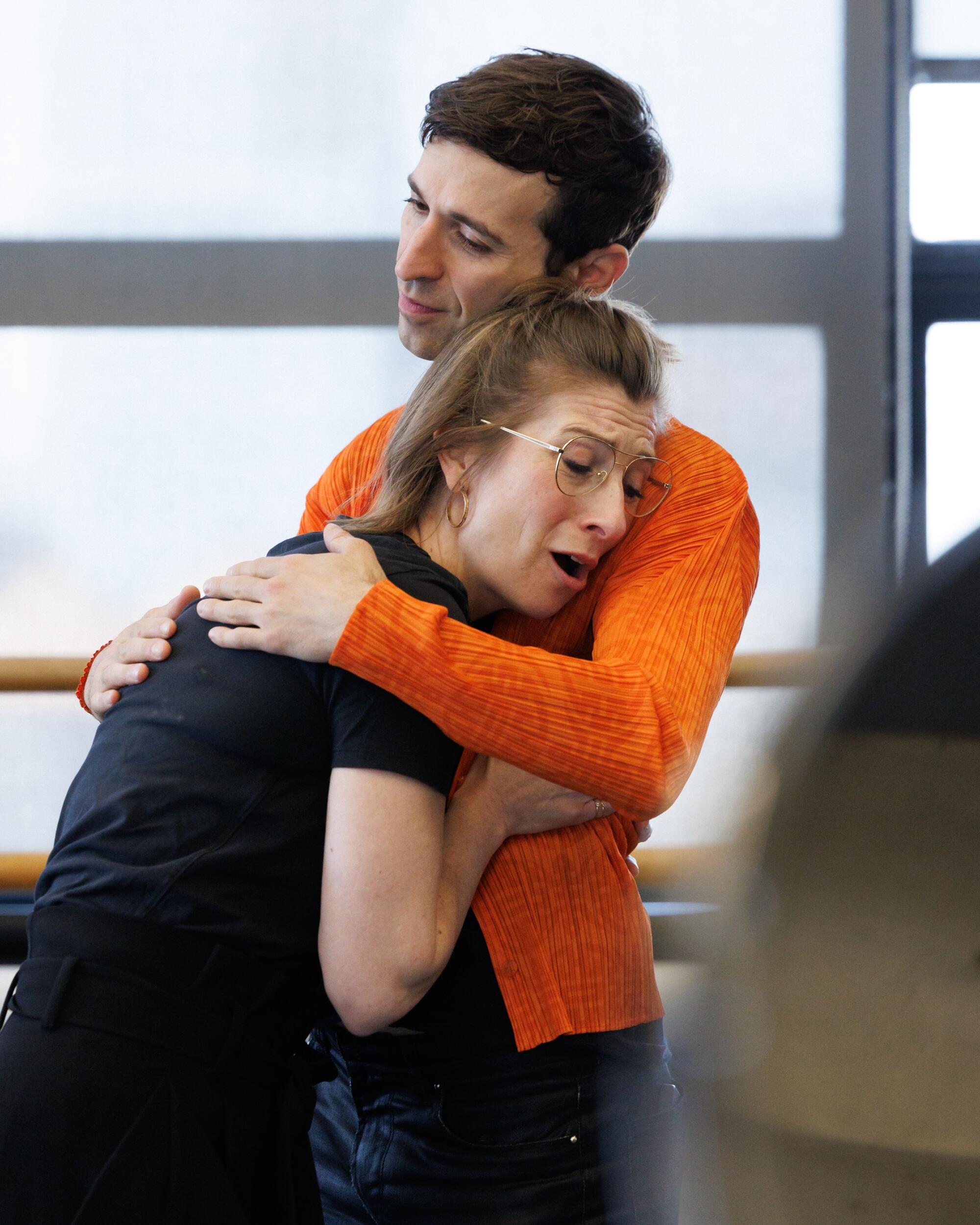 Kiera Duffy and Anthony Roth Costanzo, in an orange jacket, hug while rehearsing a scene for "The Comet / Poppea."