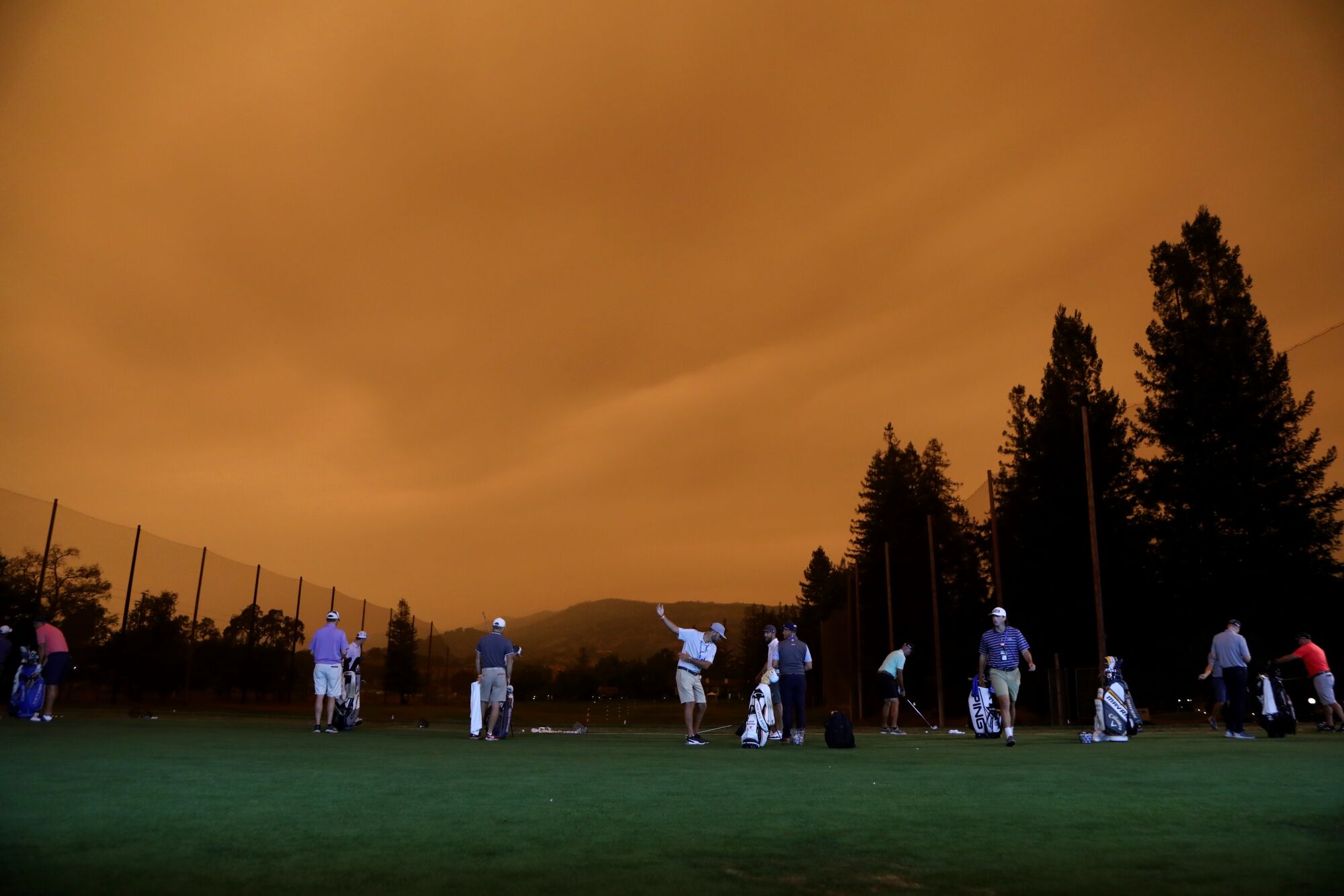 Golfers warm up under orange skies during the preview day of the Safeway Open at Silverado Country Club in Napa.