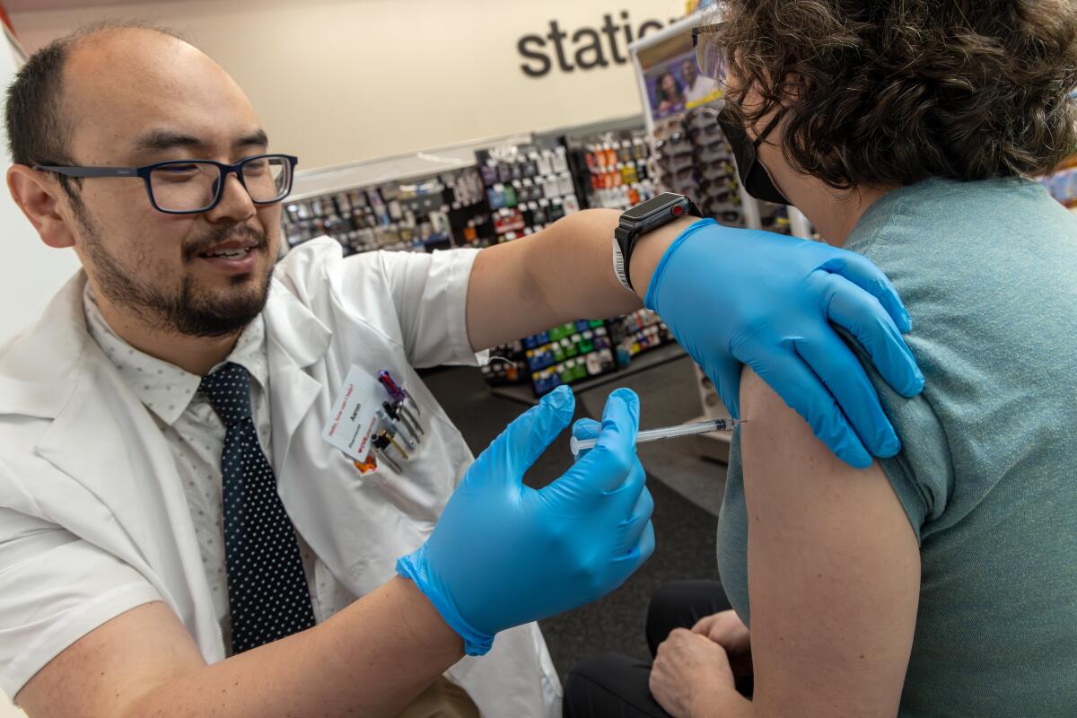EAGLE ROCK, CA - SEPTEMBER 14: Pharmacist Aaron Sun administers new vaccine COMIRNATY (COVID-19 Vaccine, mRNA) by Pfizer, to Jennifer Grappone at CVS Pharmacy in Eagle Rock, CA. (Irfan Khan / Los Angeles Times)
