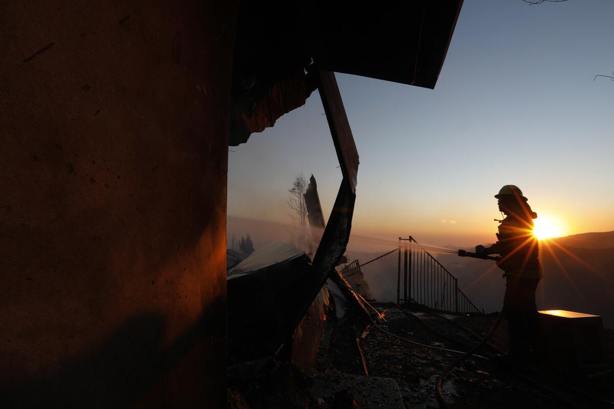 Firefighter Ken Williams puts out a hot spot on a fire-ravaged home along Linda Flora Drive in Bel-Air.