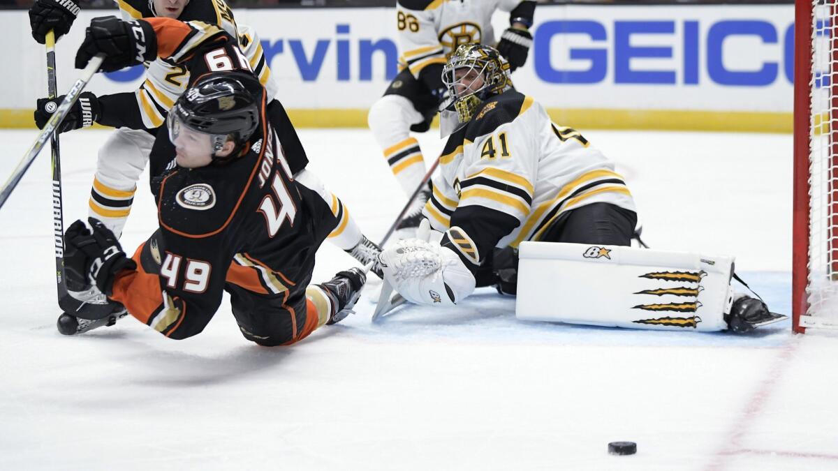 Boston Bruins goaltender Jaroslav Halak, right, deflects a shot as Ducks left wing Max Jones, left, falls during the second period.