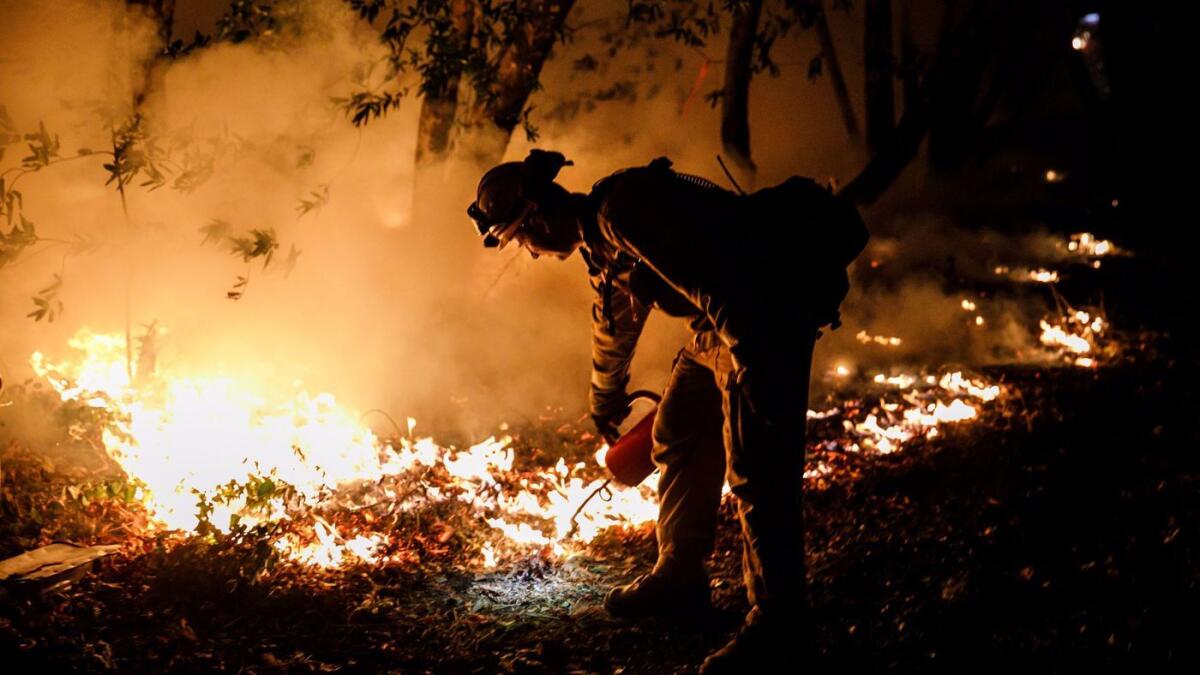 A firefighter works to prevent flames from crossing Highway 29, north of Calistoga, Calif., on Oct. 12, 2017.