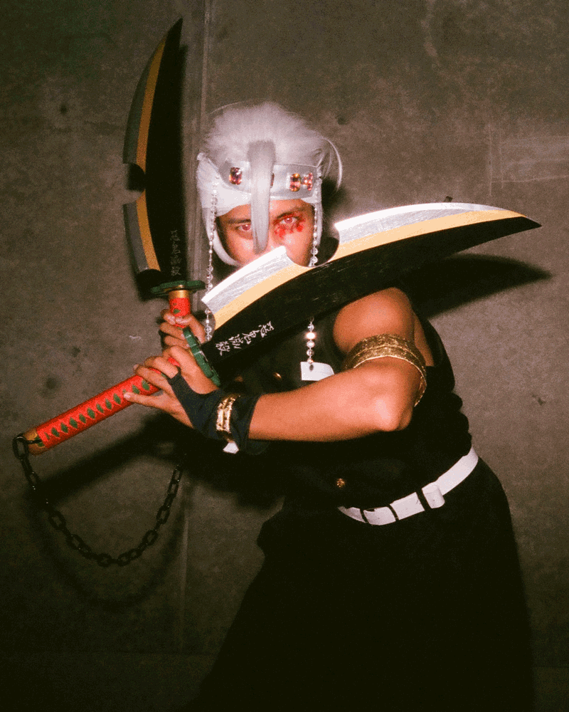 A gif of a cosplayer with two large bladed weapons.