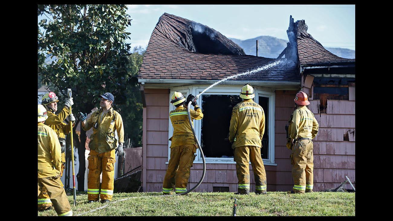 A Los Angeles County firefighter aims water at the smoldering roof of a home that was destroyed by fire overnight on Milmada Drive in La Cañada Flintridge on Wednesday, April 25, 2018. Arson investigators looked for clues as to how the fire started at the home, which was under construction. One construction truck parked on the driveway also showed signs of damage.