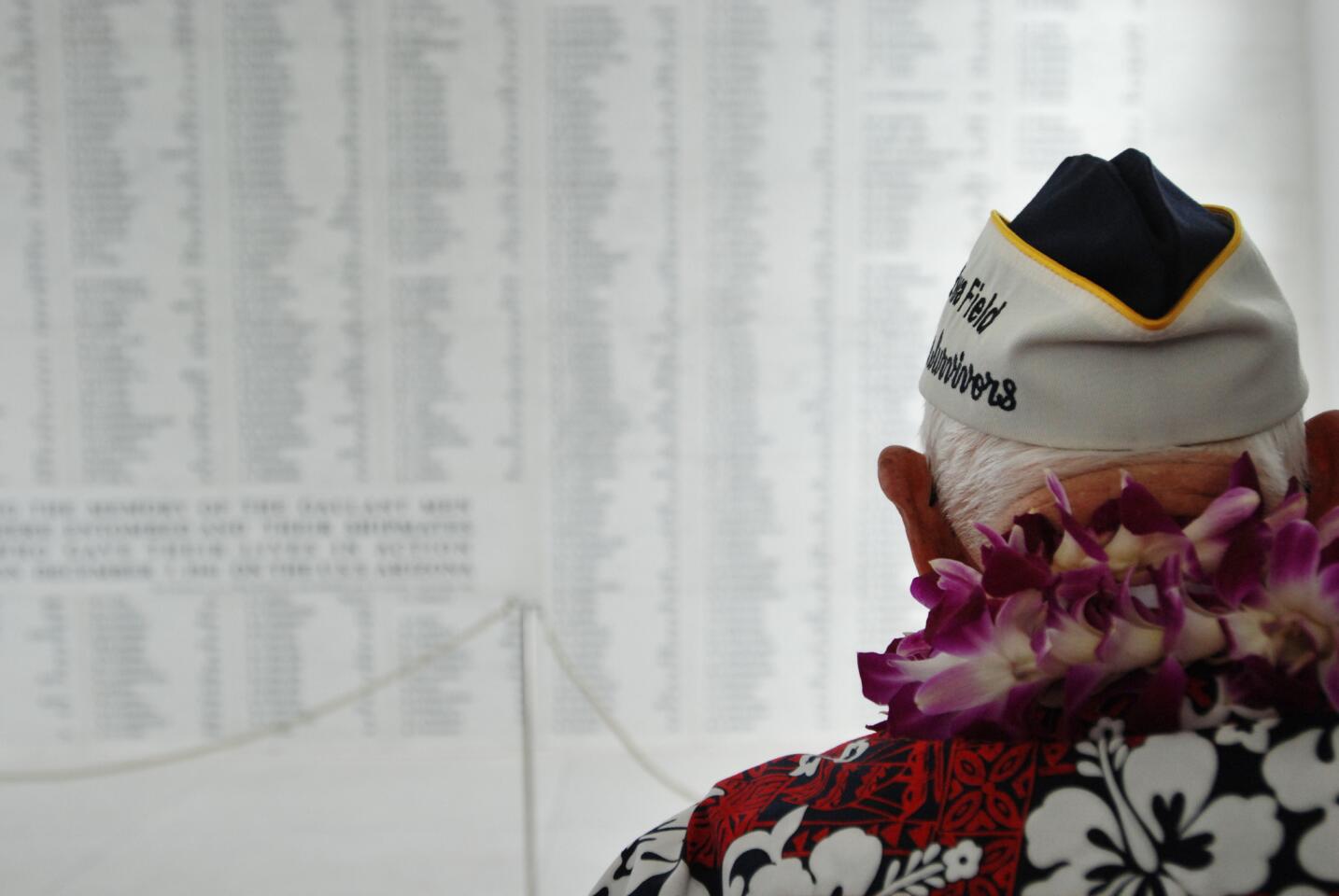 Pearl Harbor survivor John Hughes pauses to look at a wall engraved with the names of USS Arizona sailors and Marines killed in the attack on Pearl Harbor after a wreath-laying ceremony at the USS Arizona Memorial in Pearl Harbor, Hawaii, Monday, Dec. 7, 2015. A memorial and a wreath-laying ceremony were marking the 74th anniversary of the Japanese attack. (AP Photo/Audrey McAvoy)
