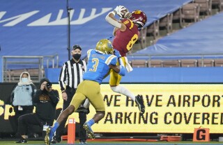 El jugador de la USC Amon-ra St. Brown atrapa el pase de touchdown ganador mientras es defendido por Rayshad Williams de UCLA el 12 de diciembre de 2020.