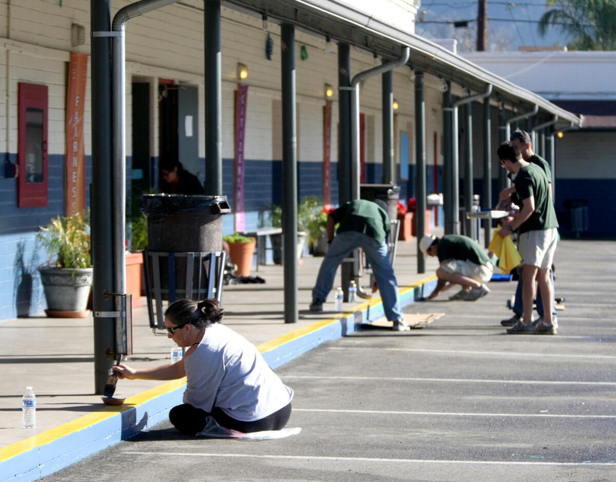 Providence High School Engish teacher Annie Matthews, front, helps paint the school yard at Our Lady of the Holy Rosary in Sunland on Tuesday, January 6, 2015. Providence High School faculty and staff volunteered to paint the library and school yard of the elementary school as a service project.