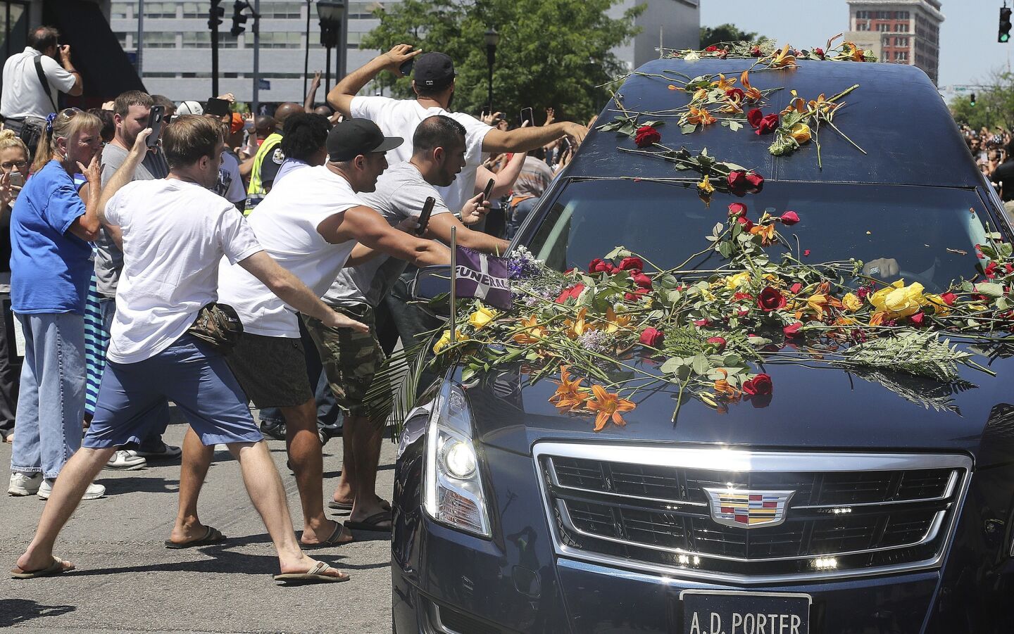 Men reach out to touch the hearse carrying the body of Muhammad Ali as it drives down Broadway toward the Cave Hill Cemetery.